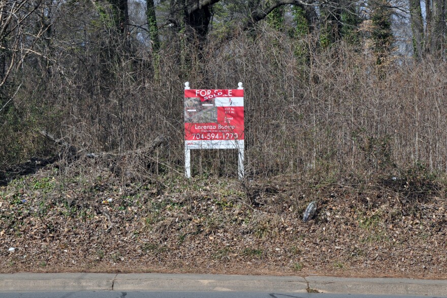 Sign on overgrown lot saying sold