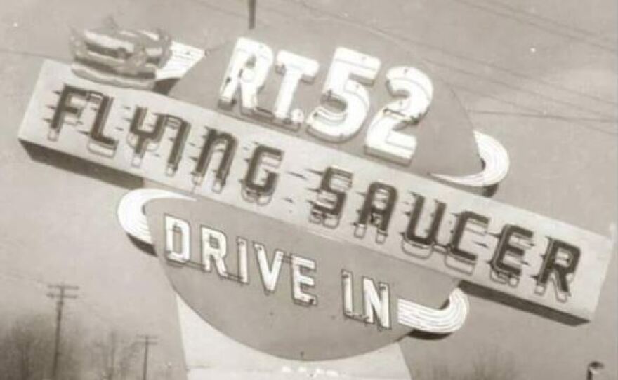 A black and white photograph of a roadside sign reading Rt. 52 Flying Saucer Drive In.