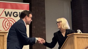 A man and a woman shake hands at a podium 