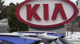 the company logo for kia stands behind a row of cars