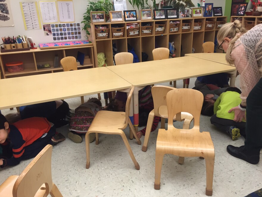 Preschoolers huddle beneath a table at Green Tree Early Learning Center in Seattle, which conducts monthly earthquake drills.