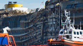 A Coast Guard patrols in front of the severely damaged right side of the Costa Concordia cruise ship after it was righted last week.