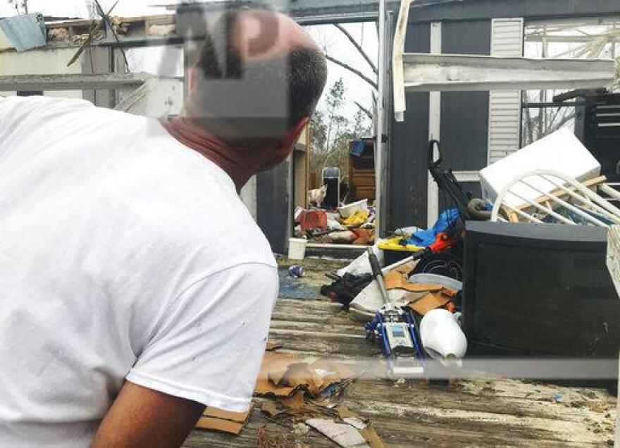 In this Oct. 23, 2018 photo, Mark Ward surveys the destruction of his neighbor's mobile home in Bay County, Fla. Ward and his neighbors say that the rural parts of the county have seen little help since Hurricane Michael.