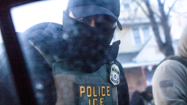A masked U.S. Immigration and Customs Enforcement agent knocks on a car window in Minnesota on Jan. 12, 2026.
