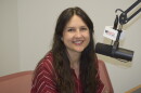 A woman sits in front of a microphone and smiles 