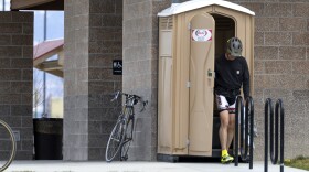 A passing cyclist uses the porta potty next to the public restroom, with doors locked, at the Dos Rios Park, April 4, 2024, in Grand Junction. Public restrooms have become harder and harder to find.