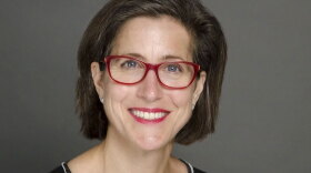 Kelly McBride press photo - woman with brown hair and red-rimmed glasses
