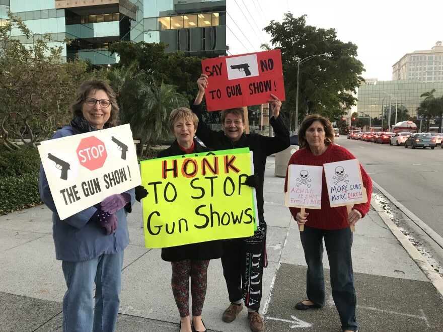 women standing with signs to end gun shows