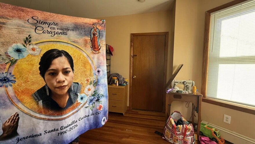 A man holds up a blanket with the image of his wife created for him by a local funeral home, Jeronima Quinilla Castro de Cos, who died by suicide on July 22.
