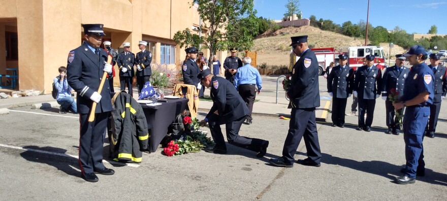 First Responders and members of the public on Monday lay roses next to a table signifying the fire fighters lost during the 9/11 terrorist attacks