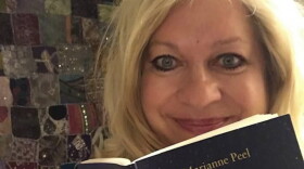 Marianne Peel faces camera holding her book titled No Distance Between Us