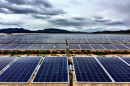 A large solar farm, with solar panels stretching out in the distance towards far-away mountains.