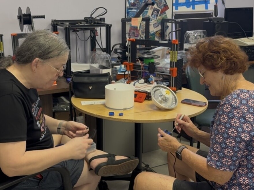 Clare Holman (left) explains to an attendee how to repair her cat’s water fountain.