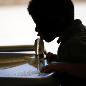 A child drinks from a water fountain.