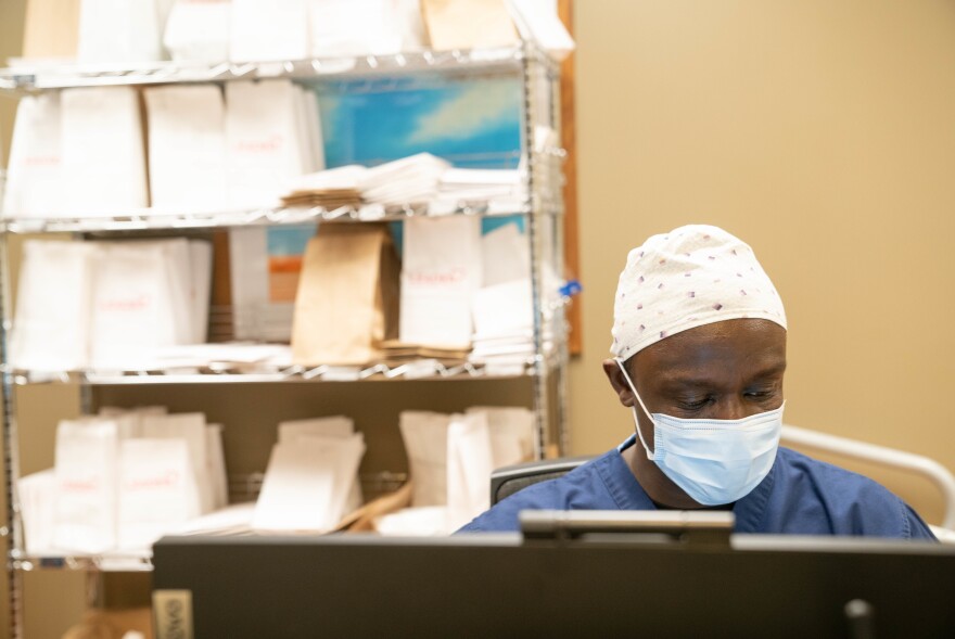 Travel Nurse Michael Niynaku, tasked with treating COVID-19 patients for the day, at a nurses' station in front of baggies containing staff members' N95 masks.