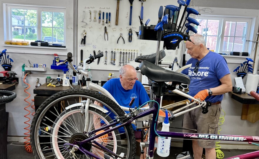 Joe Cress and another volunteer repair a mountain bike at the Wheelhouse at Elm Street Church in Lima.
