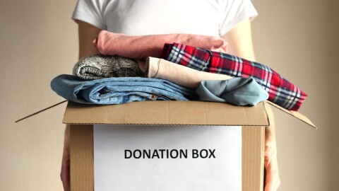 person holds a box with clothing donations
