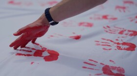 FILE - People cover a sheet in handprints at an event marking Red Hand Day, also known as the International Day against the Use of Child Soldiers, in Bogota, Colombia, where illegal armed groups recruit children, Feb. 12, 2026.
