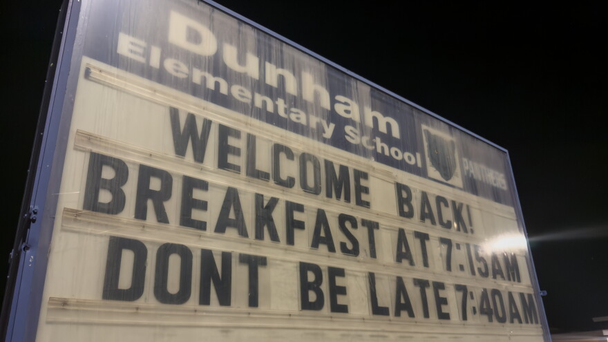 A sign outside Dunham Elementary School reading "Welcome Back! Breakfast at 7:15 AM, Don't Be Late 7:40 AM"