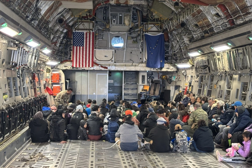 People sit on the floor of a cargo plane.