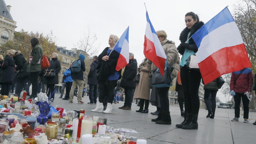 People hold French flags on the Place de la Republique in Paris on Friday. A subdued France paid homage to those killed two weeks ago.