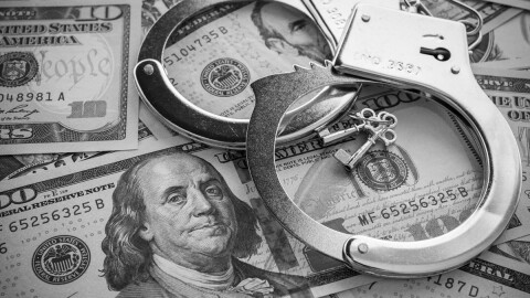 Pair of metal police handcuffs on US dollar banknotes 