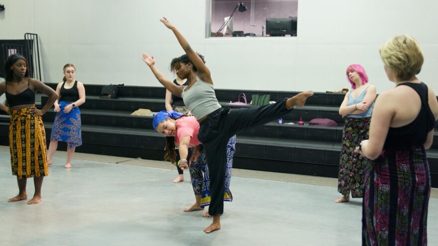 Dance instructor gives instruction to dancer balancing on one leg.