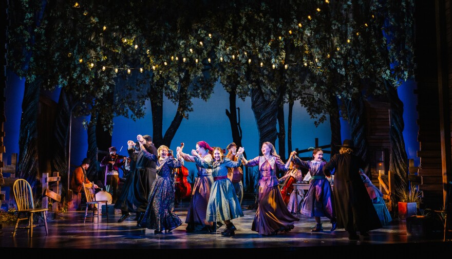 A large group of actors on stage, bathed in theatrical lighting, perform a dance in a production of the musical, Fiddler on the Roof.