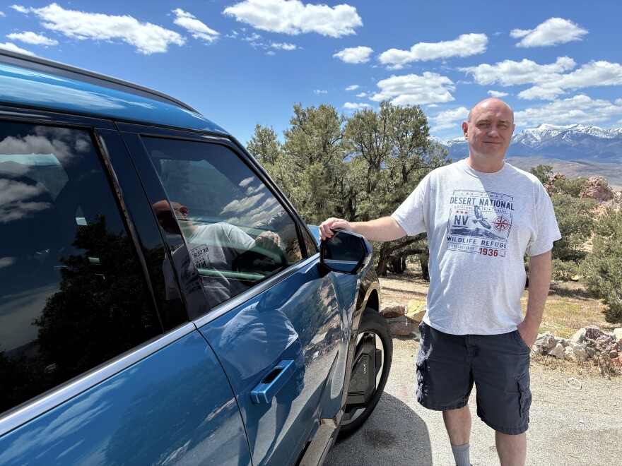 Scott Allison, standing next to his Kia EV9, stops at an overlook along Geiger Grade on the way from Reno to Virginia City.