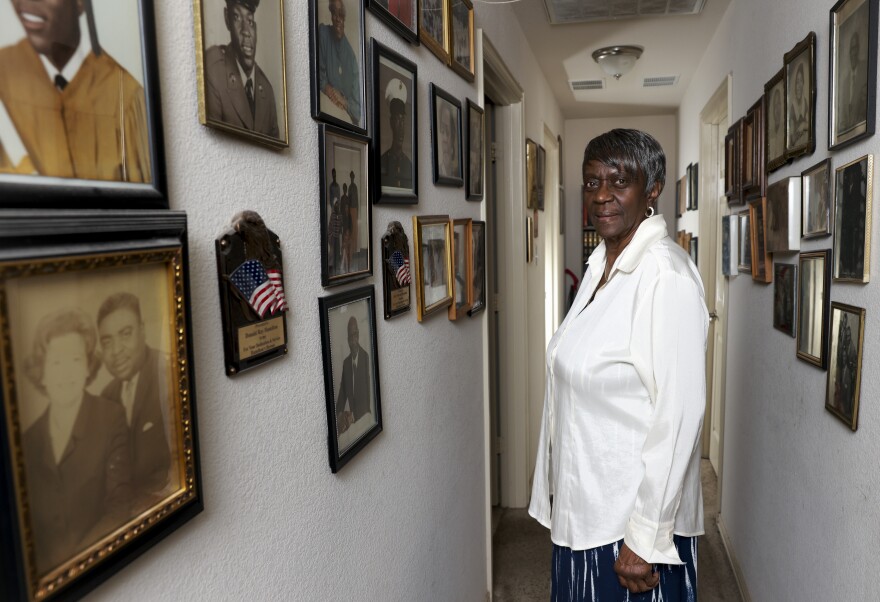 A woman stands in a hallway with pictures on both walls.