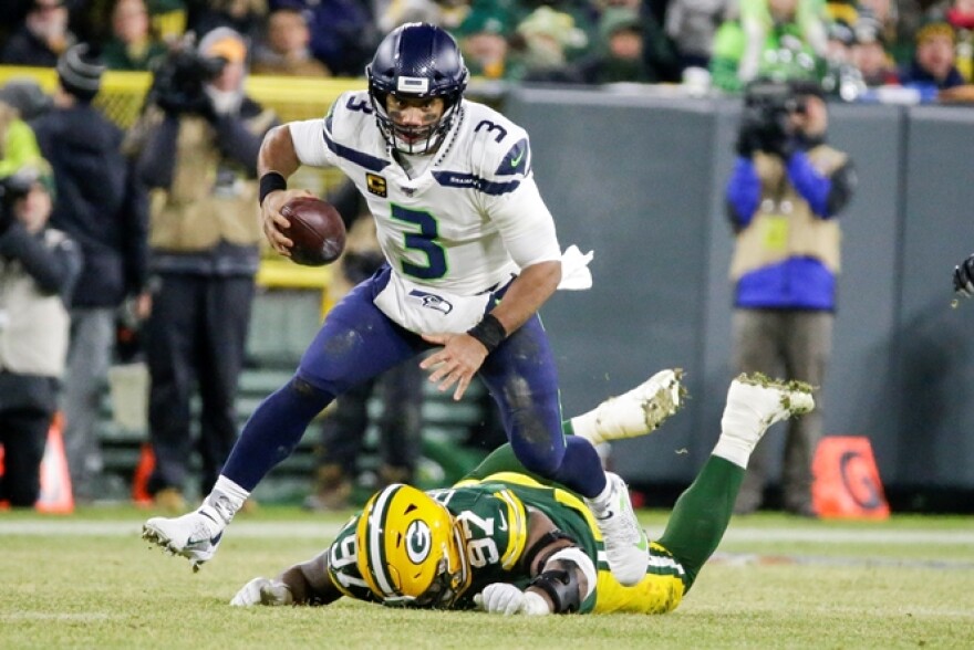Seahawks' quarterback Russell Wilson runs past Green Bay Packers' Kenny Clark for a first down during the first half of an NFL divisional playoff football game Sunday, Jan. 12, 2020, in Green Bay, Wis. 
