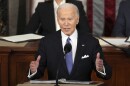 Joe Biden gestures while talking in front of two people.
