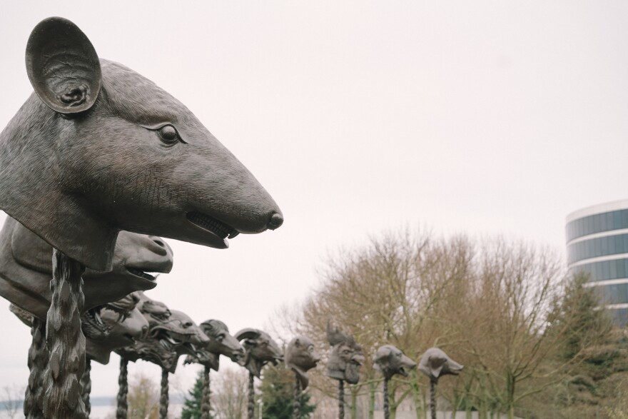 A bronze sculpture of a rat head is part of a circle of sculptures of animal heads. 