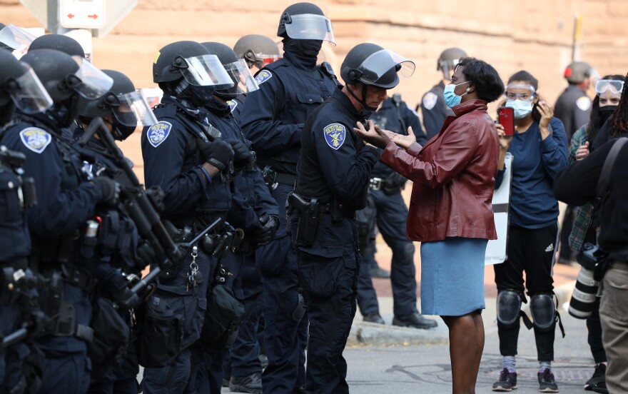 The Rev. Myra Brown, wearing a surgical mask, stands with her hands out, palms up, negotiating with Rochester police during a Sept. 16, 2020 Black Lives Matter protest outside City Hall in downtown Rochester.