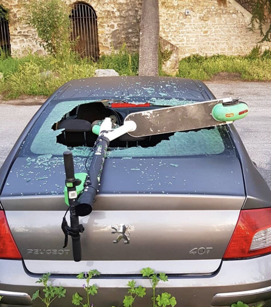 E-scooter resting on a car that has a broken windshield. Courtesy: @birdgraveyard 