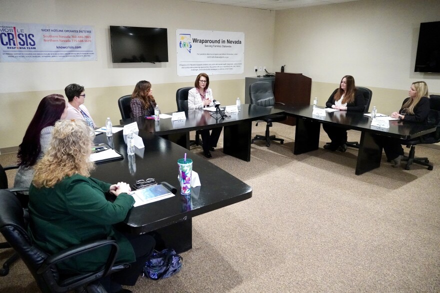 Conference tables set up in a letter U configuration. There are people sitting along the outside of the tables, looking toward one person who is speaking.