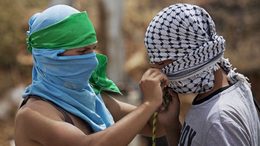 A Palestinian with a green headband, which identifies him as a Hamas supporters, helps a fellow protester with a black-and-white scarf, the symbol of the Fatah movement. They were both taking part in a demonstration near the West Bank city of Ramallah on June 4. The factions agreed to end their feud earlier this year, but many of their supporters remain bitter rivals.