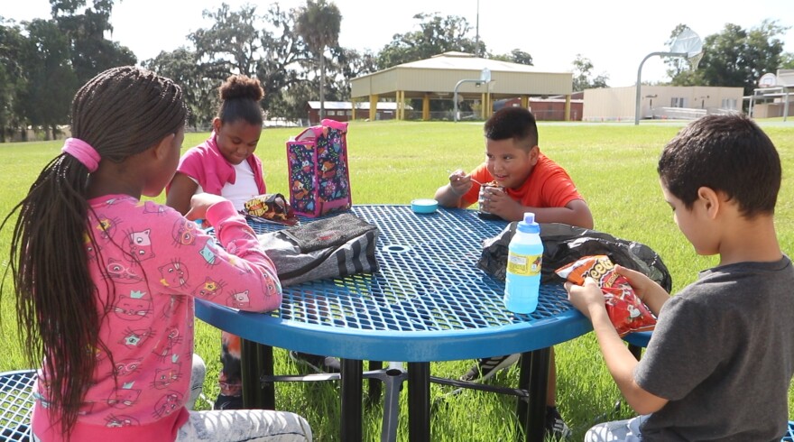 Pasco County Schools photo of four children sitting outside a school building