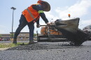 A man shovels hot asphalt during a parking lot