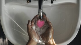 A person washing their hands with heart shaped soap. (Getty Images)
