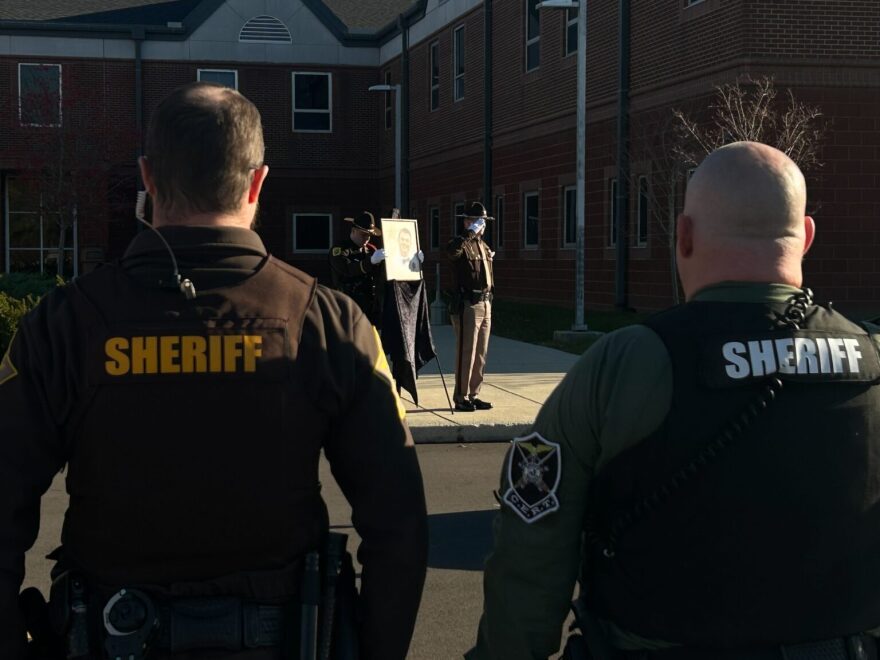 Officer Jax Ohda holding a photo of Corporal Reynolds while his 10-42 call was given.