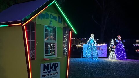 Small green hut with lights in background, sign reading “Whoville Cocoa Hut” 