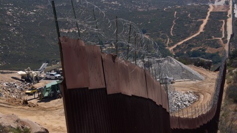 Construction crews work on a new border wall segment near the end of a previously built section on Kuuchamaa Mountain, Friday, April 24, 2026, seen from Tecate, Mexico. (AP Photo/Gregory Bull)