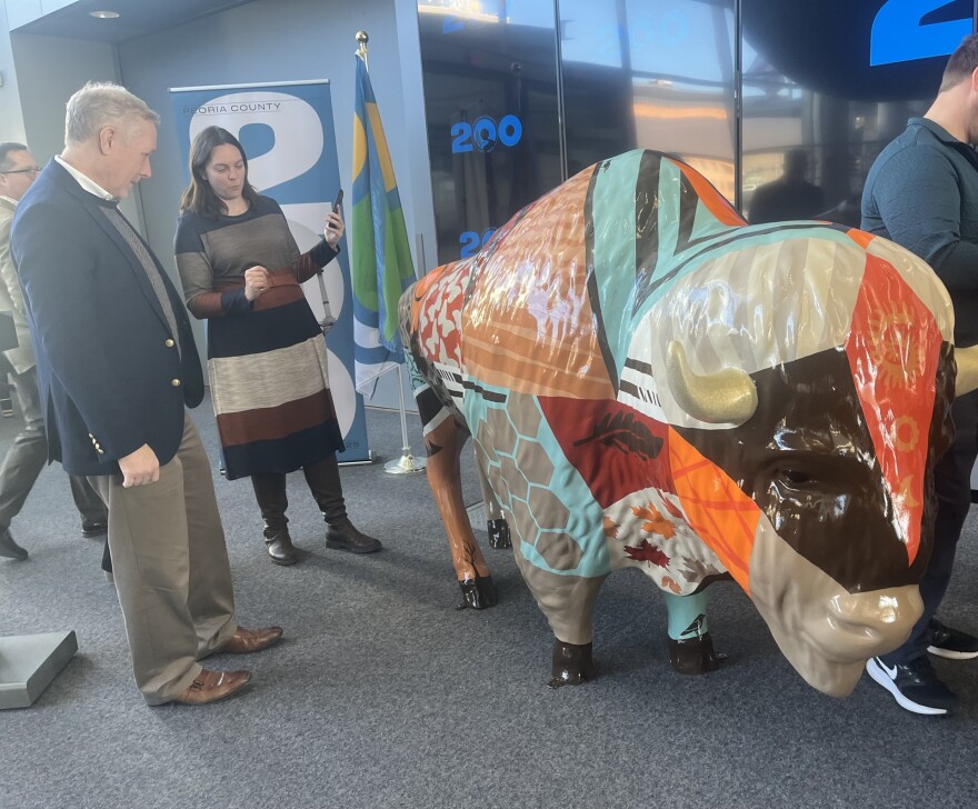 Peoria County board member Rob Reneau (left) and County Communications Director Gretchen Pearsall (right) examine artist Linda Webb's geometrically painted bison statue.