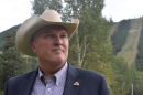 A man in a cowboy hat looks off into the distance.