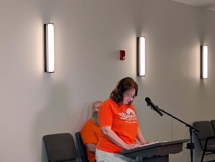 Kelly Keleman stands at a podium with her head down. 