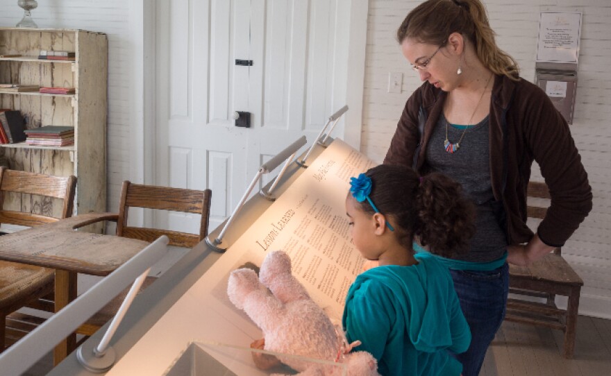 A young girl and a woman read an exhibit installation in the schoolhouse.