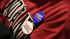 A supporter of Democratic presidential candidate Hillary Clinton wears campaign buttons as she listens to former President Bill Clinton at an event in Indiana.