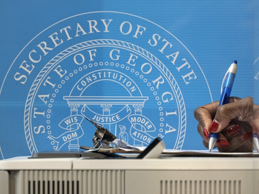 In this Dec. 14, 2020, file photo, a voter fills out paperwork before casting a ballot the first day of early voting for the Senate runoff election in Atlanta.