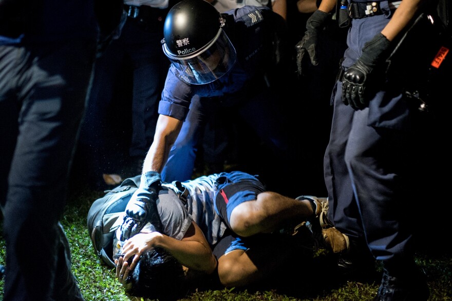 A police officer detains a pro-democracy protester after he was tackled to the ground in Hong Kong.